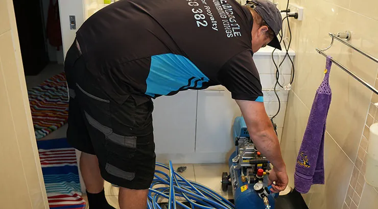 Plumber relining a drain through a bathroom floor waste