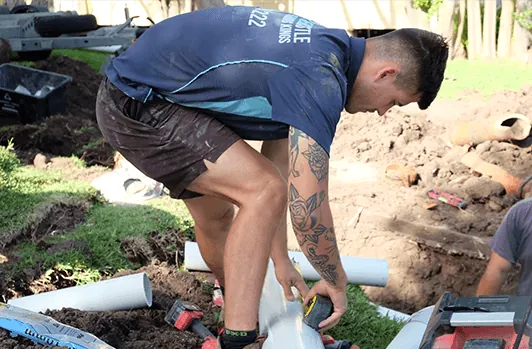 Plumber laying new pipe in an open trench